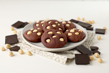 Tasty chocolate cookies with hazelnuts on white table, closeup