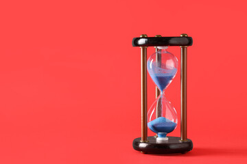 Stylish hourglass with blue sand on red background