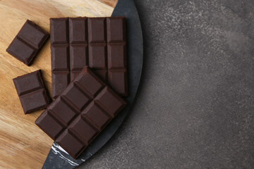 Pieces of delicious dark chocolate on brown table, top view. Space for text