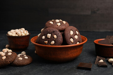 Tasty chocolate cookies with hazelnuts on black table