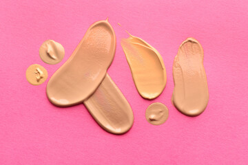 Foundation on pink background, top view. Smears of cosmetic product