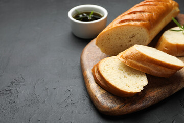 Cut fresh baguette with balsamic on black table, closeup. Space for text