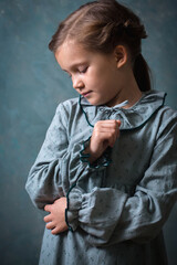 A young girl is wearing a vintage gray-green dress