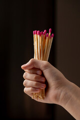 A hand holding a bunch of matches with a pink and red tip