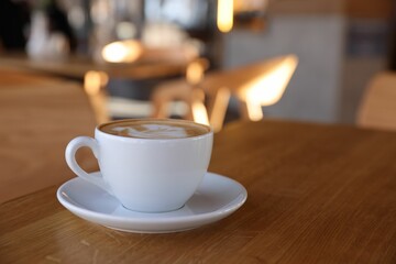 Cup of aromatic coffee on wooden table in cafe, closeup. Space for text