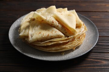 Tasty crepes on wooden table, closeup view