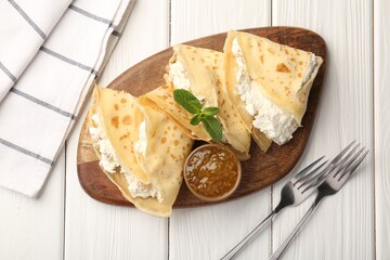 Delicious crepes with cottage cheese, jam and mint served on white wooden table, top view