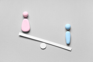 Scales with female and male figures made of plasticine on grey background