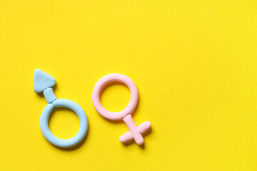 Male and female gender symbols made of plasticine on yellow background