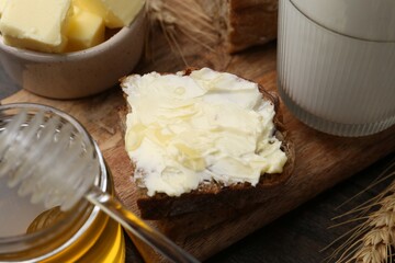 Tasty sandwich with butter, honey and milk on wooden table, closeup