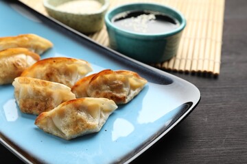 Fried gyoza dumplings and soy sauce on wooden table, closeup