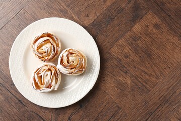 Freshly baked apple roses on wooden table, top view. Space for text