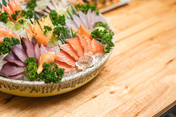 A beautifully arranged Japanese sashimi platter with fresh salmon, and shellfish on ice, garnished with vegetables., tuna, white fish