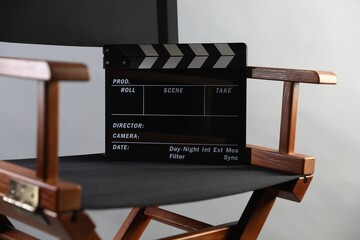 Director's chair with clapperboard on light grey background, closeup