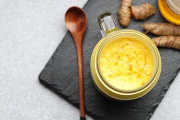 Delicious turmeric latte with honey and rhizomes on grey table, top view