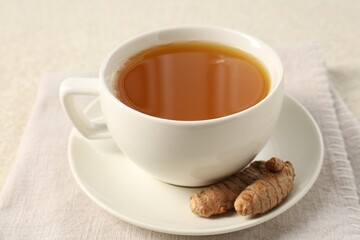 Fototapeta premium Aromatic turmeric tea and rhizomes on white textured table, closeup