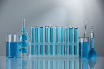 Laboratory glassware with blue liquid on mirror surface against grey background