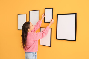 Woman hanging blank photo frames on wall in room