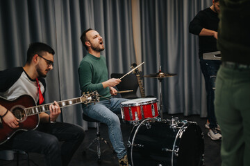 Fototapeta premium A group of musicians performing in a modern studio setting, displaying teamwork and creativity. The scene showcases individuals playing guitar and leading vocals while practicing their craft.
