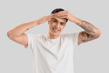 Young man doing face building exercise on light background