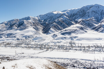 A village in a mountain valley of Kyrgyzstan in winter. Sunny winter day in the mountains.