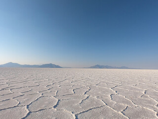 Fototapeta premium A tranquil morning on Bonneville Salt Flats, where the unbroken landscape stretches endlessly beneath a pristine blue sky.