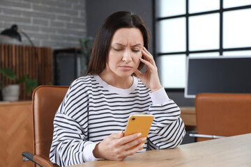 Worried woman with mobile phone in office