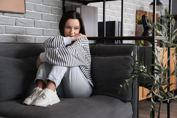 Worried woman sitting on sofa at home