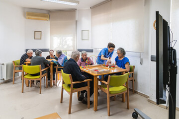 Nurse helping senior residents during board game activity in nursing home