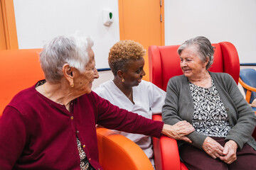 Caring nurse engaging with elderly women in nursing home