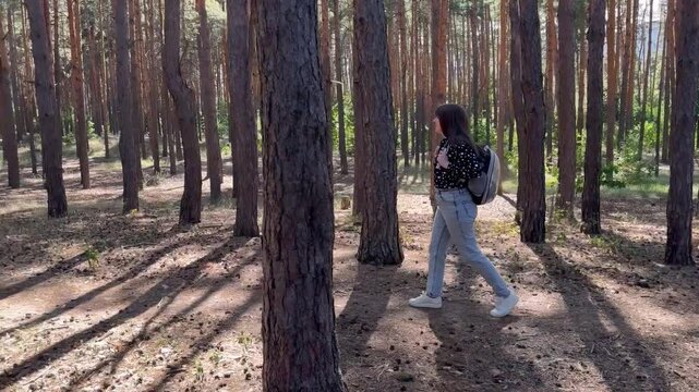 Woman walks in forest with cat in carrier and backpack