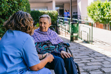Caring nurse interacting with elderly woman outdoors