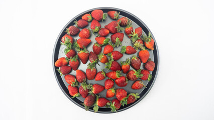 Several strawberries being held in the hand and on a tray