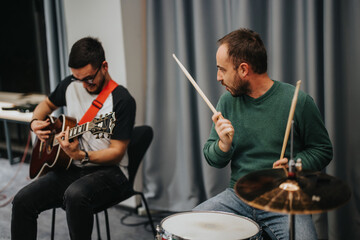 Fototapeta premium Two musicians, one playing an acoustic guitar and the other on drums, perform energetically in a music studio setting, showcasing their passion for music and teamwork during a lively band practice