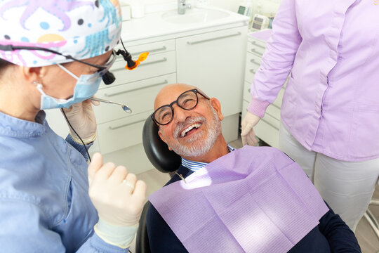 Senior man smiling during dental checkup with dentist and assistant