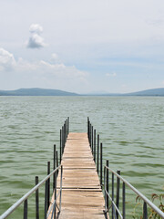 Obraz premium Cuexcomatitlan pier in the water, cloudy sky, in Cajititlan lake with a cloudy sky in the background. The water is green and calm