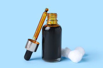 Bottle with iodine, pipette and cotton wool on blue background, closeup