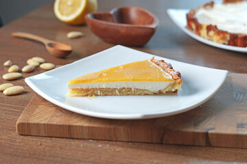 Slice of cake on plate of almond flour and natural fruit in kitchen. Nuts on table. Healthy food and products. Organic ingredients and vegan nutrition. 