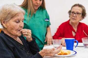 Elderly caregiver assisting seniors during mealtime