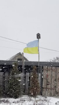 Snowfall with Ukrainian flag waving in a rural area