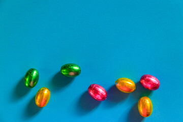 Easter chocolate eggs in foil on blue background. Top view