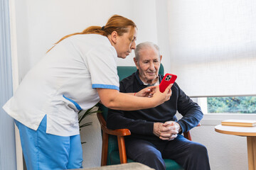 Nurse assisting elderly man with smartphone technology