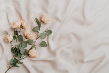 A delicate arrangement of beige roses with green leaves placed on softly draped fabric, creating a romantic and minimalistic aesthetic.
