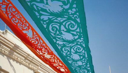 Vibrant Festive Banners:  A captivating low-angle view of vibrant orange and teal decorative banners strung overhead, their intricate cutouts casting delicate shadows.