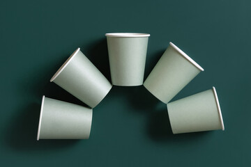 Disposable light green paper cups on a dark green top view, mockup. Sustainable lifestyle