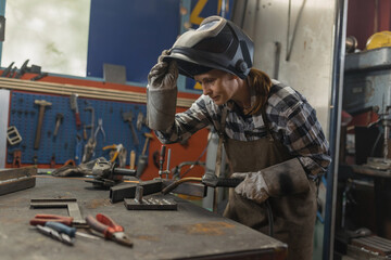 Woman welder successfully performing the MIG welding process in the family business workshop....