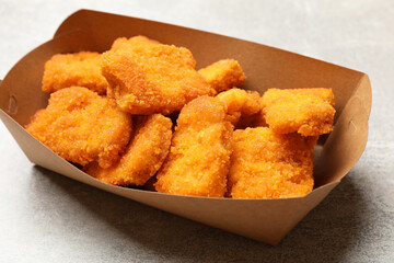 Delicious chicken nuggets in carton box on light table, closeup
