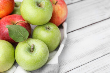 Different whole ripe apples on white wooden table, closeup. Space for text