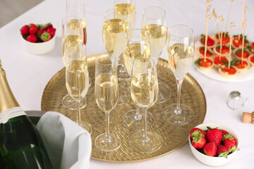 Champagne, strawberries and canapes with red caviar on white table