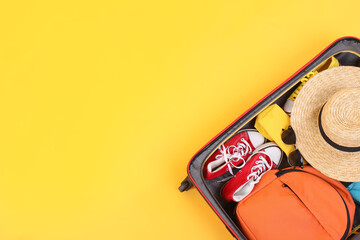Travel abroad. Packed suitcase on yellow background, top view. Space for text